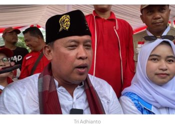 Tri Adhianto Memakai Peci Bergambar Pahlawan Nasional KH. Noer Ali Sebagai Tanda Hormat 
